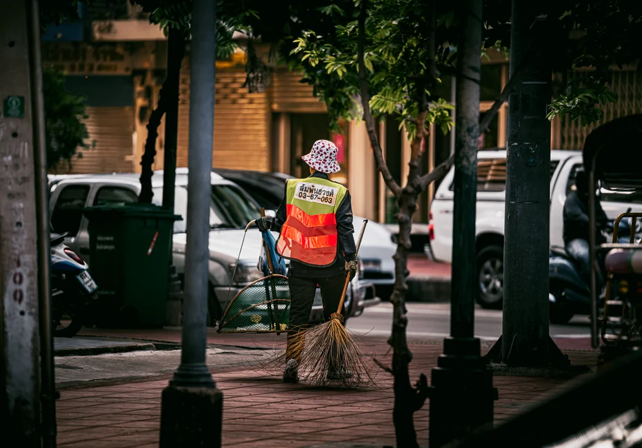 about-us-02 Cleaning crew in red uniforms with equipment approaching a modern house exterior.
